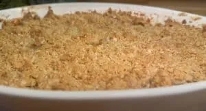 Golden apple crumble dessert in a white baking dish, with a crispy oat topping, ready to serve.